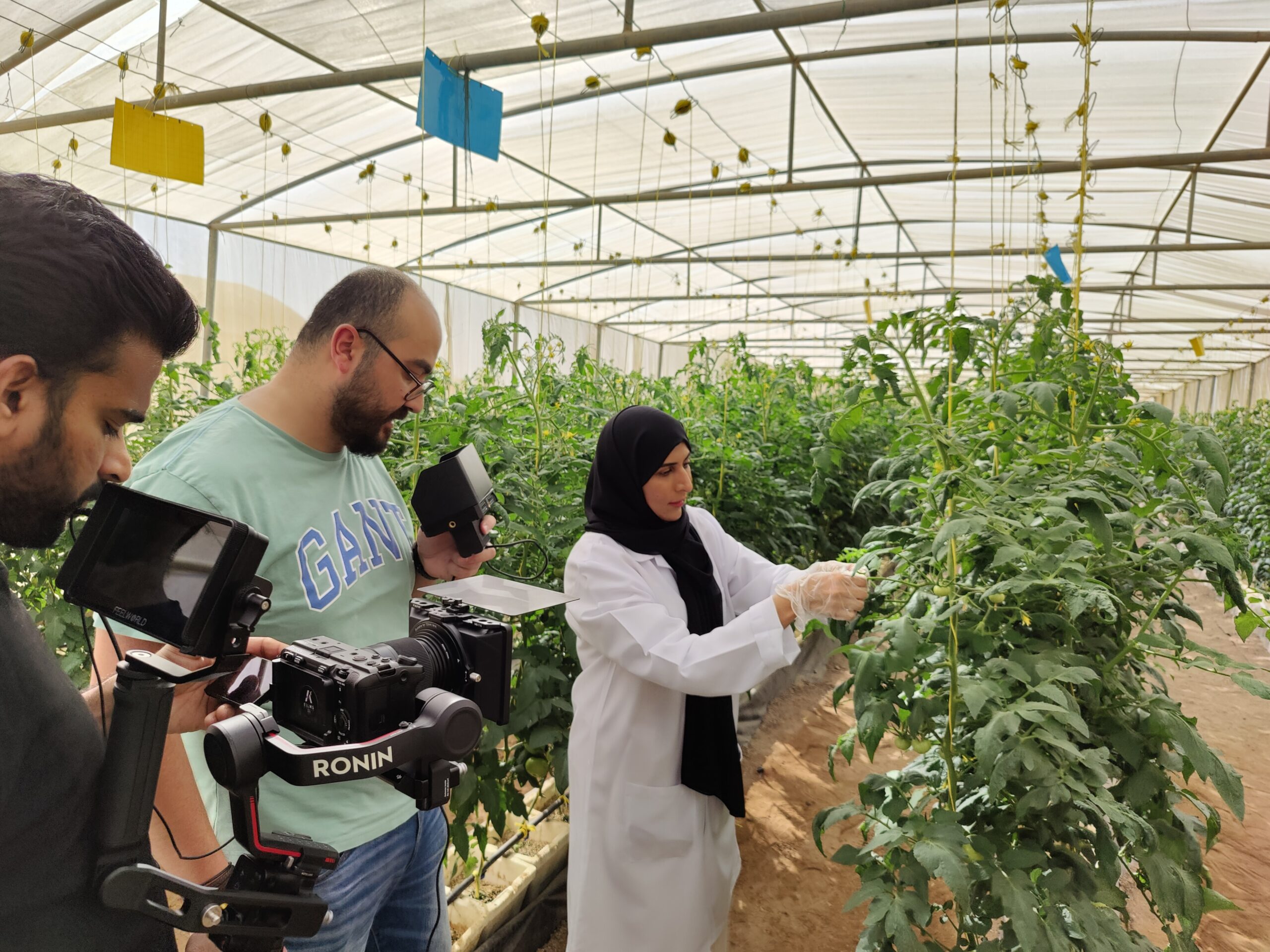 A cameraman is shooting video of group of people in traditional Middle Eastern attire having meeting at conference table.