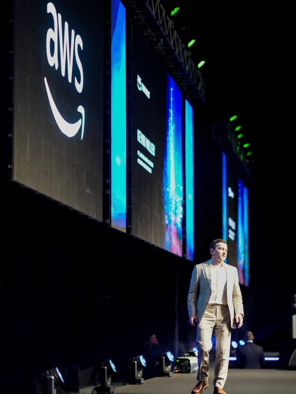 A photographer takes pictures of two men posing in front of a white backdrop. Studio lighting equipment surrounds them.